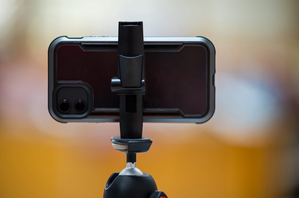 A mobile phone mounted on a tripod for teaching students online.