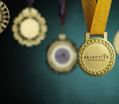 Close-up photograph of awards hanging against a dark green background with a Selective Insurance logo.